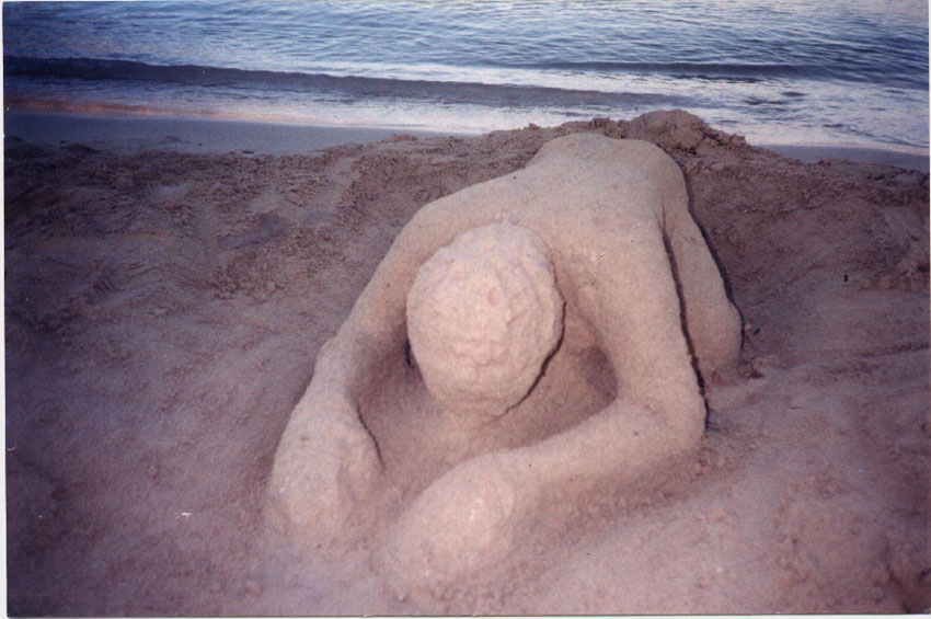Sand Sculpture of man crawling out of the sea