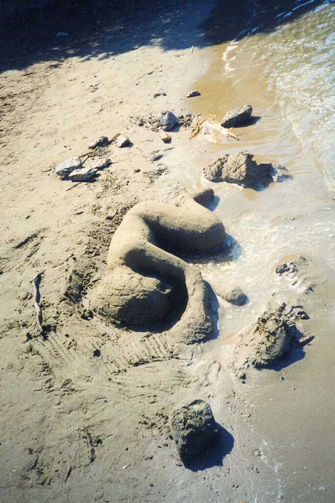 sand scuptrure of a female figure laying on her side by the seashore